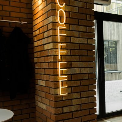 Coffee neon sign emblem in neon style on brick wall background.